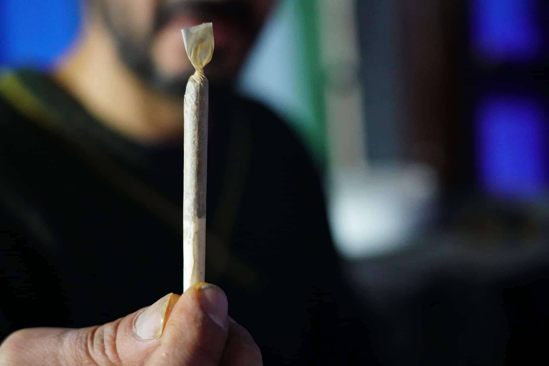 A man holds up an unlit joint