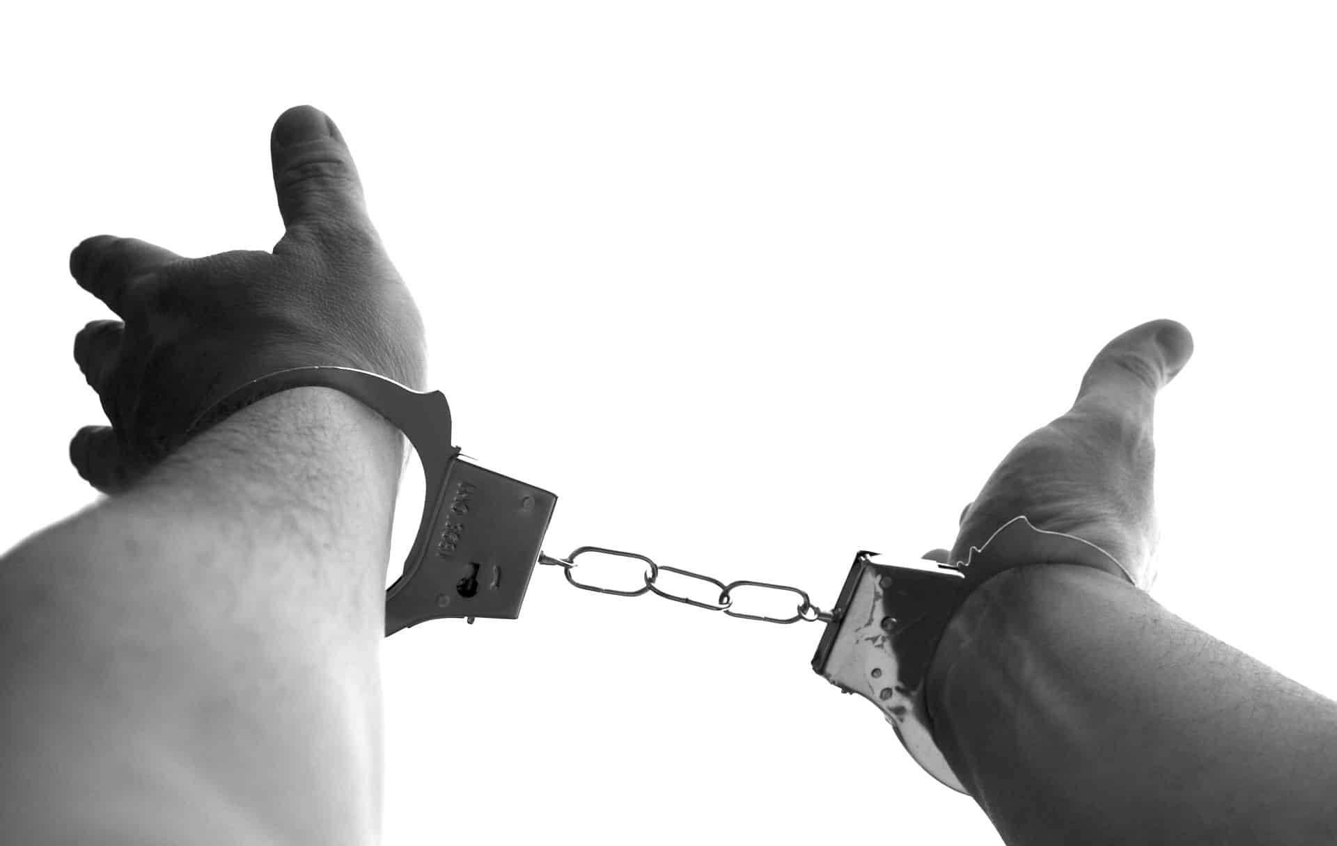 Two hands reach out in handcuffs